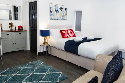 a bedroom with a king sized bed and a couch at Snuggle Cove Apartments- Walton Road in Liverpool