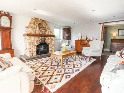 a living room with a stone fireplace and white furniture at Stoneycross Cottage in Preston