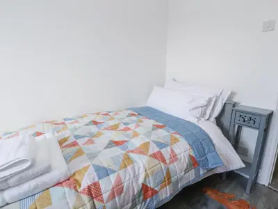 a bed with a colorful quilt on top of it at Stoneycross Cottage in Preston
