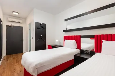 two beds in a room with red and white at Tune Hotel Liverpool in Liverpool