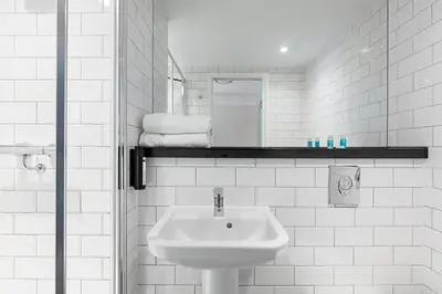 a white bathroom with a sink and a mirror at Tune Hotel Liverpool in Liverpool