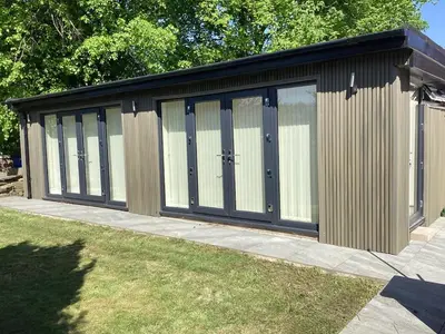 a large wooden building with four sliding doors at Golf view lodge in Lostock