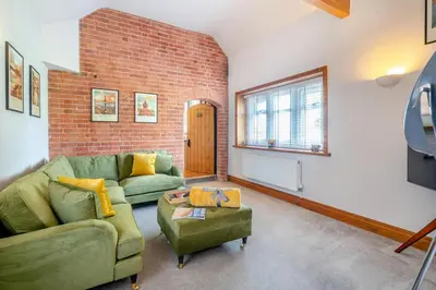 a living room with a green couch and a brick wall at 1 Bed in Weeton oc-c32015 in Great Singleton