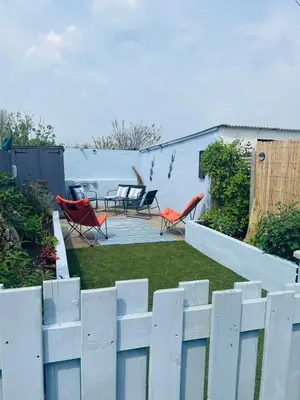 a white fence in a yard with chairs and tables at Willow Cottage Haverigg Millom in Haverigg