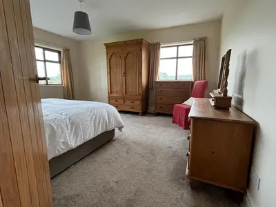 a bedroom with a bed and a dresser and two windows at Oaken Fields, Waddington, Clitheroe in Waddington