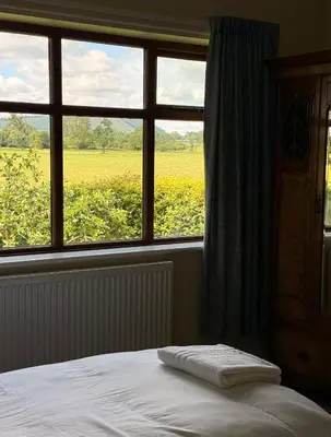 a bedroom with a bed and a window with a field at Oaken Fields, Waddington, Clitheroe in Waddington