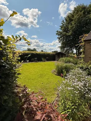 a yard with a field of grass and flowers at Oaken Fields, Waddington, Clitheroe in Waddington