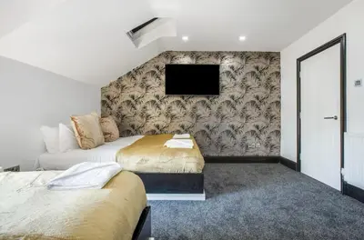 a bedroom with two beds and a tv on a wall at New Mixies Manor in Blackpool