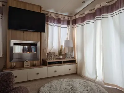 a living room with a flat screen tv and curtains at Private Caravan to Hire - Marton Mere Haven Holiday Village in Blackpool