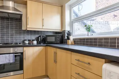a kitchen with wooden cabinets and a window at Free Parking, 4 Bed, 2 Bath House, Long Term Stay Savings, Contractors, Near Anfield in Liverpool