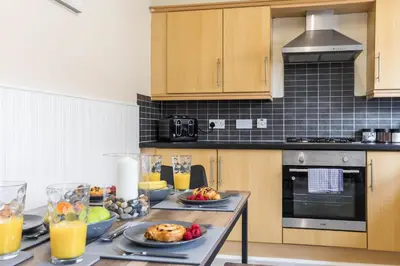 a kitchen with a table with food and orange juice at Free Parking, 4 Bed, 2 Bath House, Long Term Stay Savings, Contractors, Near Anfield in Liverpool