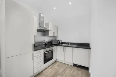 a white kitchen with a sink and a microwave at GuestReady - Gladstone in Liverpool