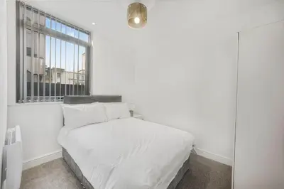 a white bedroom with a bed and a window at GuestReady - Gladstone in Liverpool