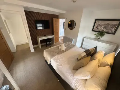 a bedroom with a bed and a desk and a television at The Hideaway - 2-Bedroom Apartment with outdoor terrace & free parking in Lancaster