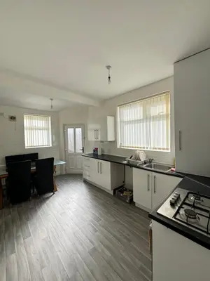 an empty kitchen with white cabinets and a table at Cozy Double Room with 5 Minute Walk to Anfield Stadium ideal for Matchdays in Liverpool