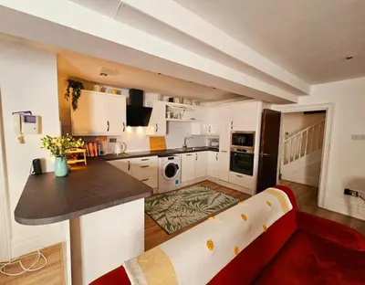a kitchen with white cabinets and a red couch at Liverpool Georgian Quarter Apartment in Liverpool