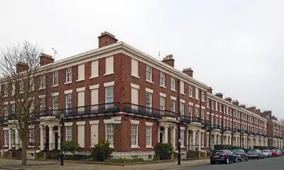 a large brick building with cars parked in front of it at Liverpool Georgian Quarter Apartment in Liverpool