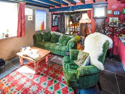 a living room with green couches and a table at Rainbow Cottage in Vickerstown