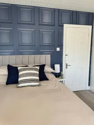 a bedroom with a large bed with a blue wall at Beachside Home-Pizza Oven & Bar Close To Beach and Town in Cleveleys