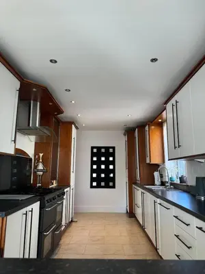 a large kitchen with white cabinets and black appliances at Beachside Home-Pizza Oven & Bar Close To Beach and Town in Cleveleys
