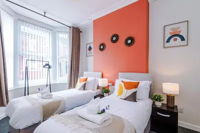 two beds in a room with an orange wall at Stylish 3-Bed Home in Liverpool by 53 Degrees Property, Ideal Great for Large Groups & Business, Sleeps 8! in Liverpool