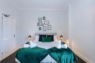 a white bedroom with two beds with green sheets at Stylish 3-Bed Home in Liverpool by 53 Degrees Property, Ideal Great for Large Groups & Business, Sleeps 8! in Liverpool