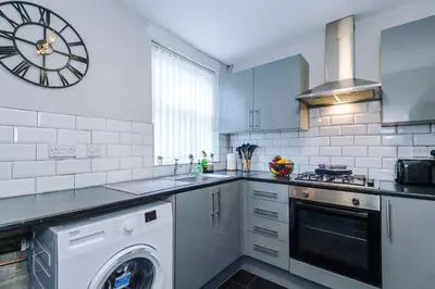 a kitchen with a washer and a clock on the wall at Stylish 3-Bed Home in Liverpool by 53 Degrees Property, Ideal Great for Large Groups & Business, Sleeps 8! in Liverpool