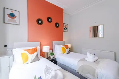 two beds in a room with an orange wall at Stylish 3-Bed Home in Liverpool by 53 Degrees Property, Ideal Great for Large Groups & Business, Sleeps 8! in Liverpool