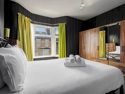 a bedroom with a large white bed with yellow curtains at Liverpool, Anfield 3 Bed Home, Parking & Wifi - Pass the Keys in Liverpool