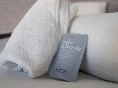 a bottle of hair and body cream next to towels at Liverpool, Anfield 3 Bed Home, Parking & Wifi - Pass the Keys in Liverpool