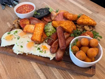 a plate of breakfast food with eggs sausage potatoes and beans at Top Floor Apt Promenade Sea Views Sleeps 6 Shore Vibes in Morecambe