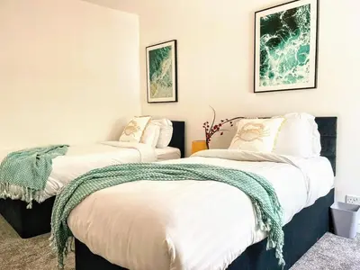 two beds in a room with white walls at Top Floor Apt Promenade Sea Views Sleeps 6 Shore Vibes in Morecambe