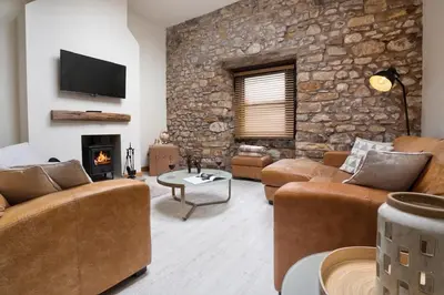 a living room with couches and a stone wall at The Old Paper-shop, WiFi, Sleeps 4 & Pet Friendly in Bolton le Sands