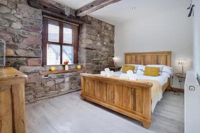 a bedroom with a large bed and a stone wall at The Old Paper-shop, WiFi, Sleeps 4 & Pet Friendly in Bolton le Sands