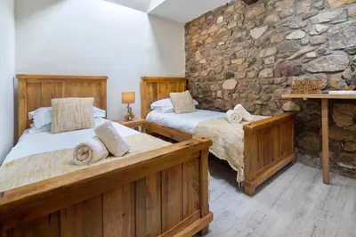 two beds in a room with a stone wall at The Old Paper-shop, WiFi, Sleeps 4 & Pet Friendly in Bolton le Sands