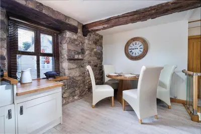 a kitchen with a table and chairs and a clock at The Old Paper-shop, WiFi, Sleeps 4 & Pet Friendly in Bolton le Sands
