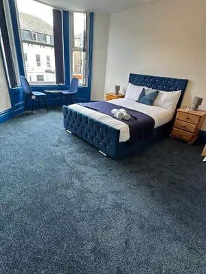 a bedroom with a large bed with a blue headboard at Elite Hotel Blackpool in Blackpool