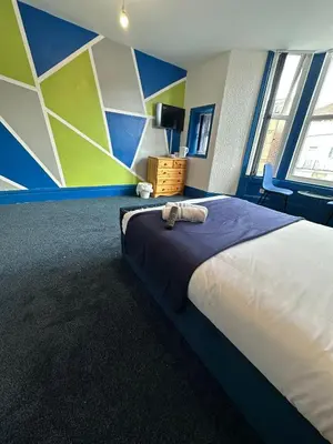 a bedroom with a bed with a blue and green wall at Elite Hotel Blackpool in Blackpool