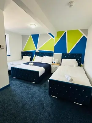 two beds in a room with blue and yellow walls at Elite Hotel Blackpool in Blackpool