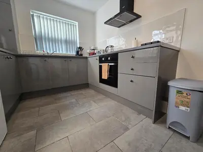 a kitchen with white cabinets and a tile floor at Cozy Home in Liverpool in Liverpool