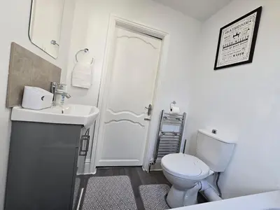 a white bathroom with a toilet and a sink at Cozy Home in Liverpool in Liverpool