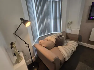 a couch sitting in a room with a window at Cozy Home in Liverpool in Liverpool