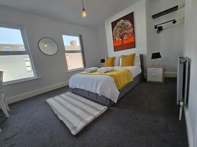 a bedroom with a bed with a yellow blanket and a mirror at Cozy Home in Liverpool in Liverpool