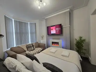 a living room with a couch and a tv on the wall at Cozy Home in Liverpool in Liverpool