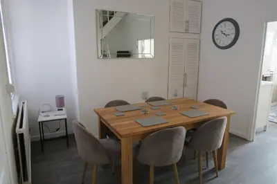 a dining room table with chairs and a clock on the wall at NEW 4 Bed house close to train station and town in Blackpool