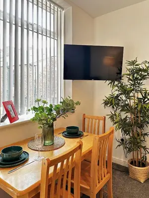 a dining room table with two chairs and a television at Wigan 1BR Haven - Perfect for a Relaxing Stay in Wigan