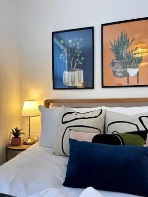 a bedroom with a white bed with paintings on the wall at Wigan 1BR Haven - Perfect for a Relaxing Stay in Wigan