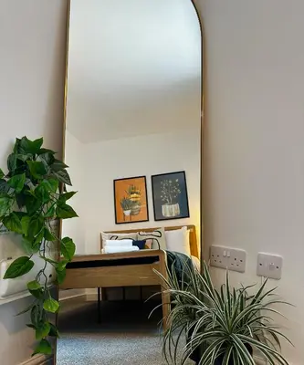 a mirror in a room with a bed and a plant at Wigan 1BR Haven - Perfect for a Relaxing Stay in Wigan