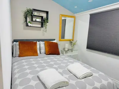 a bedroom with a bed with orange pillows and a window at Cozy Home in Bootle in Liverpool