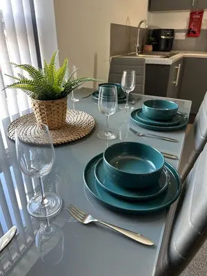 a table with plates and wine glasses on it at Ideal Wigan Base - 1BR for Cosy Stays in Wigan